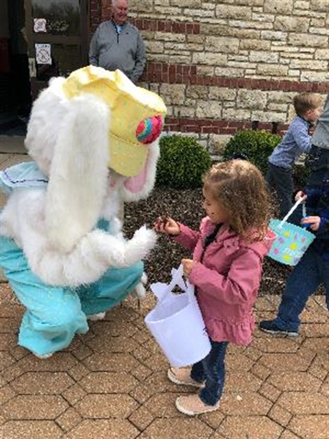 Easter Bunny handing an egg to a young girl.